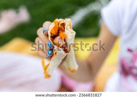 Close up of hands handling food outdoor. Child girl hand holding deletions pita. Street food concept
