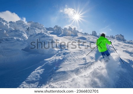 Skier skiing downhill in high mountains against the fairytale winter forest.