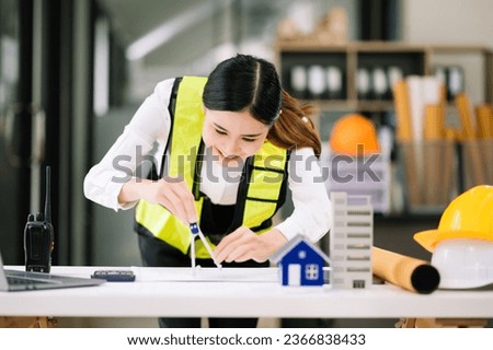 Creative architect projecting on the big drawings working and laptop with on on architectural project at construction site at desk in office. Asian woman industry professional 