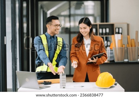  Engineer teams meeting working together wear worker helmets hardhat with on architectural project site and making model house. Asian industry professional team in modern office