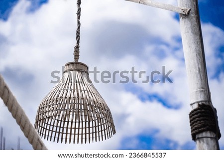 Lamp made from random fish traps bright sky background.