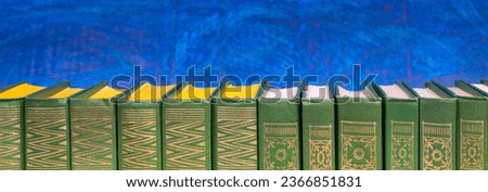 Composition with hardback books, fanned pages on wooden deck table and blue background. Books stacking. Back to school. Copy Space. Education background