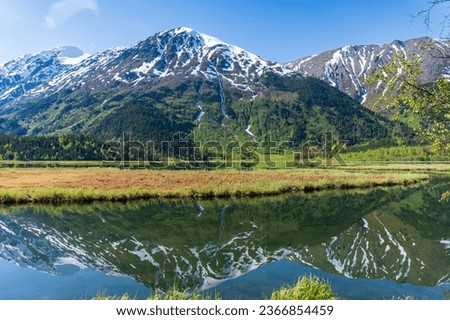 Tern Lake along Seward Highway on Kenai Peninsula in Alaska. At junction with Sterling Highway in Chugach National Forest. Mountain landscape perfectly reflected in mirror still alpine lake.  Royalty-Free Stock Photo #2366854459