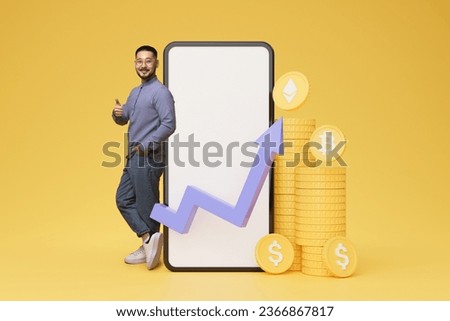 Cheerful young asian guy standing by huge phone with white blank screen, bitcoins and dollars, chart of changes on markets and stocks. Man trading online, colorful background, collage, mockup