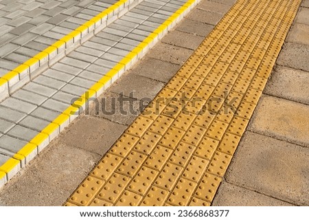 Yellow blocks of tactile paving for blind handicap.Braille blocks, tactile tiles for the visually impaired.Textured ground surface indicators located on sidewalks, stairs.