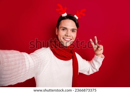 Closeup selfie of funny popular christmas blogger guy wear reindeer antlers showing v-sign enjoy recording video isolated on red color background