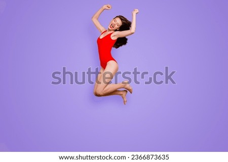 Finally, summer Full-body portrait of crazy brunett girl in red body with closed eyes jumping clenching her hands in fists and joyfully screaming isolated on yellow background
