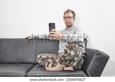 Man with glasses at home using mobile smart phone