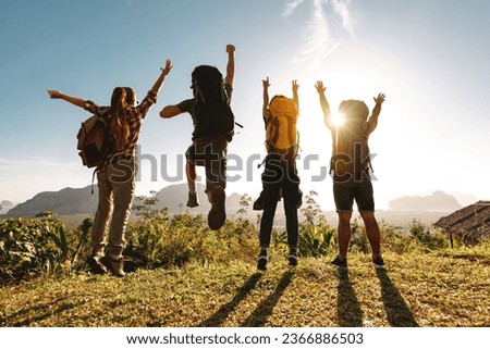 Group of happy young friends are having fun and jumps at sunrise view point with backpacks