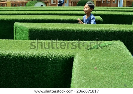 Cheerful Asian boy playing maze in park puzzle in. playing looking for a way out of the park