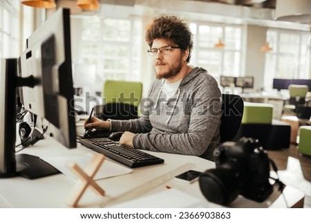 Young Caucasian photographer working on the computer in a modern business office