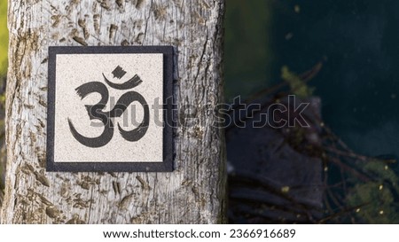 Top angle view of an Om sign on tree trunk over water. Yoga and meditation concept. Copy space