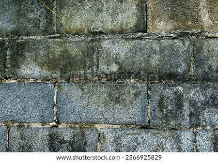 The old brick block wall is left unpainted, without plaster, and it bears stains and watermarks.
