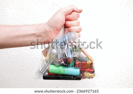 A bag full of discarded electronic cigarette vapes is being held by a white male in front of a white wall. Royalty-Free Stock Photo #2366927165