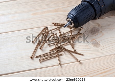 Pile of screws and screwdriver bit on a wooden table. self-tapping screw for wood