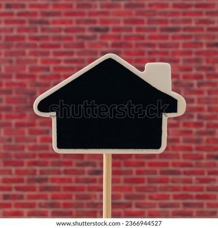 Creative layout made of black writing board in house shape against red brick wall background.  Minimal black writing board concept. Trendy background with copy space idea.