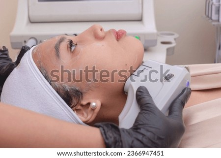 A young woman undergoing HIFU treatment for her jawline. High Intensity Focused Ultrasound technology. At a skin care, dermatologist or aesthetic clinic. Royalty-Free Stock Photo #2366947451