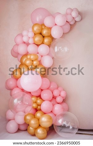 Arch with balloons for party. Beige photo wall decoration space or place for text with pink, golden balloons. Birthday party. Trendy spring decor. Celebration concept. Wedding reception.