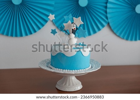 birthday cake with a snowman and blue and white stars on the table