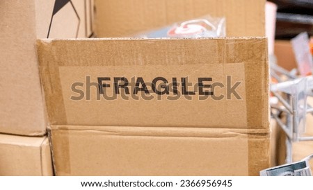An open brown cardboard box with a FRAGILE label printed on it, opened carton container with a fragile contents materials inside. Print marking, nobody transporting mailing sending easy to break items Royalty-Free Stock Photo #2366956945