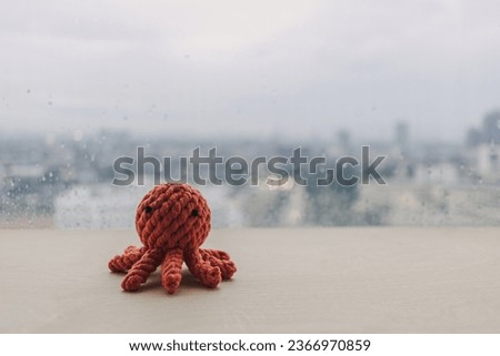 Cute red octopus handmade toy knitting doll on wooden desk with copy space.