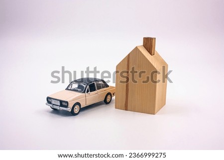 Small metal car and small one-storey house model made of wood. Photograph.