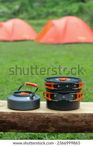 Camping equipment includes a pot and kettle with a tent as a background
