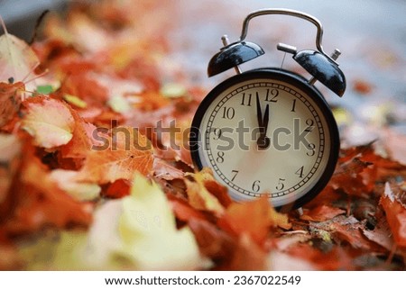 alarm clock on autumn leaves natural background Royalty-Free Stock Photo #2367022549