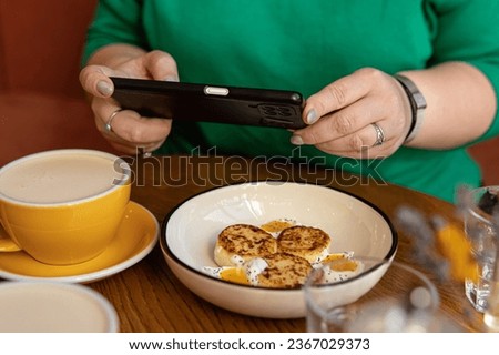Woman takes pictures of food on phone. Foodblogger. Soft focus. Breakfast and coffee in the cafe