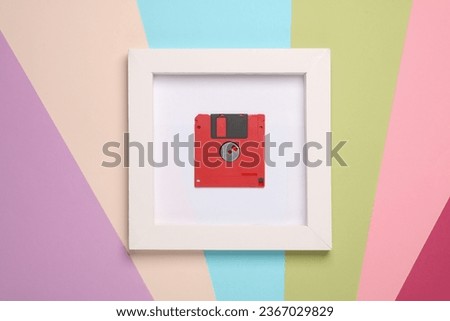 Retro 80s floppy disk in white square frame on colored background. Aesthetic minimal still life. Conceptual photo. Modern art. Top view