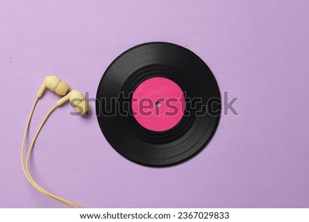 Vinyl record with headphones on magenta pastel background. Top view