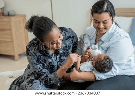 an African mother and babysitter feeding milk from bottle milk to her 2-month-old baby newborn son, to African family and food for infant concept. Royalty-Free Stock Photo #2367034037