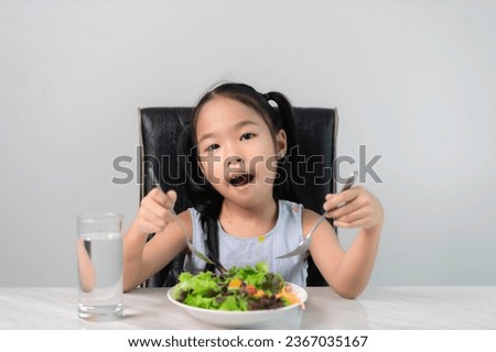 Little asian cute girl to eat healthy vegetables.Nutrition and healthy eating habits for kids concept.Children happy and like to eat vegetables.