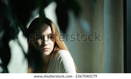 Sad young girl, teenager sitting at a cafe table in the rays of the bright summer sun Royalty-Free Stock Photo #2367040179