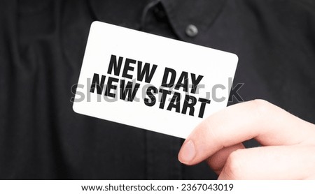 Businessman holding a card with text NEW DAY NEW START, business concept