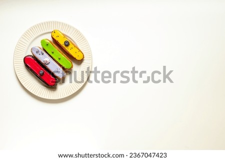 Plate of various glased eclairs cakes. Sweet food background