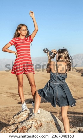 Photographer girl takes pictures of her friend in the mountains