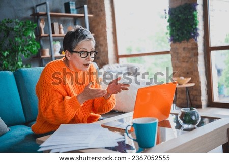 Photo of shocked excited mature lady dressed orange sweater online conference modern gadget indoors house room Royalty-Free Stock Photo #2367052555