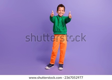 Photo of satisfied optimistic boy wear stylish green clothes two arms thumbs up nice feedback isolated on purple color background