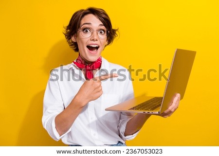 Portrait of charming astonished lady indicate finger wireless netbook isolated on yellow color background