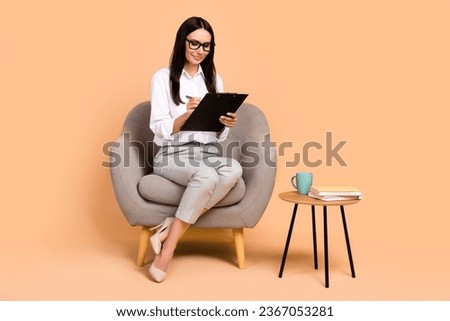 Full body portrait of classy gorgeous financier lady sitting comfort soft chair hold pen write clipboard isolated on beige color background Royalty-Free Stock Photo #2367053281