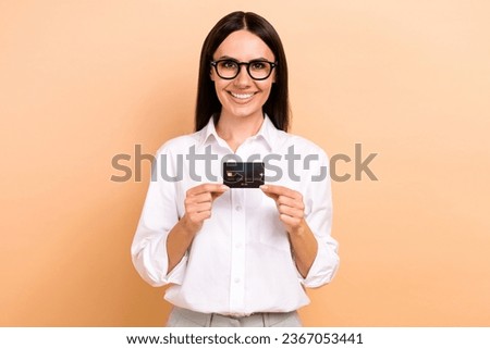 Photo of cheerful smiling lady wear white shirt spectacles showing holding bank card isolated beige color background