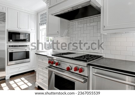 Luxury White Modern Kitchen Interior with White Cabinets with Gas Stove and Black Stone Counters Royalty-Free Stock Photo #2367055539