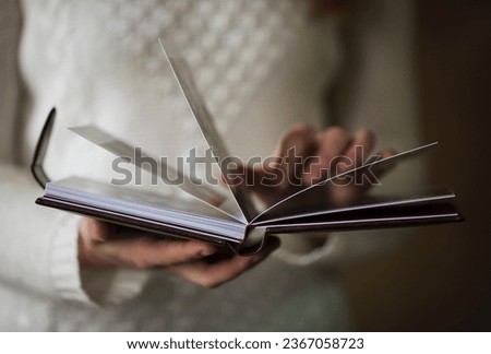 Female hands holding square photo book for wedding album. Wedding photo book, family album. Photo books with embossing and a cover of genuine leather. A book in an expensive binding. Royalty-Free Stock Photo #2367058723