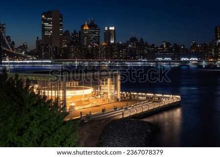 Unique view about the Jane's carousel in Brooklyn bridge park in blue hour. Manhattan's Two bridges area and East river on the foreground.