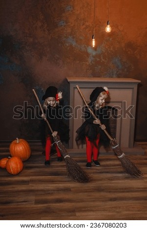 Little witches sweep the floor with brooms and play. Lanterns glow in the background. Halloween. Vertical frame.