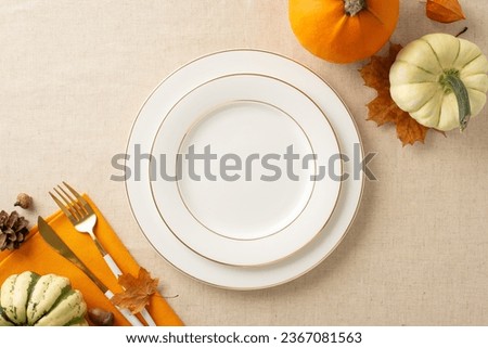 Thanksgiving feast arrangement: Top view shot of plates, napkin and cutlery on a beige tablecloth adorned with pumpkins, foliage, and pine cone. Delicate autumn vibes invite your text or message