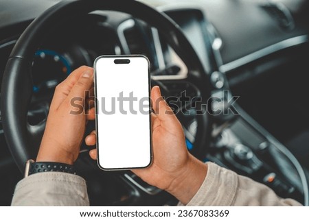 A phone with an isolated screen in the hands of a woman in a car.