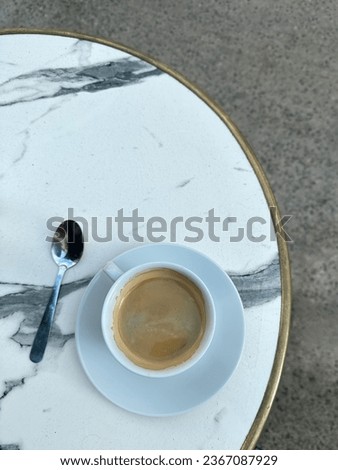 Minimalist photo, featuring a close-up of a coffee cup poised on a white table. The refined composition and neat aesthetics make it a versatile choice for various visual needs.