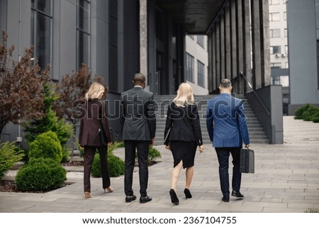 Backside photo of a business people walking toward modern office